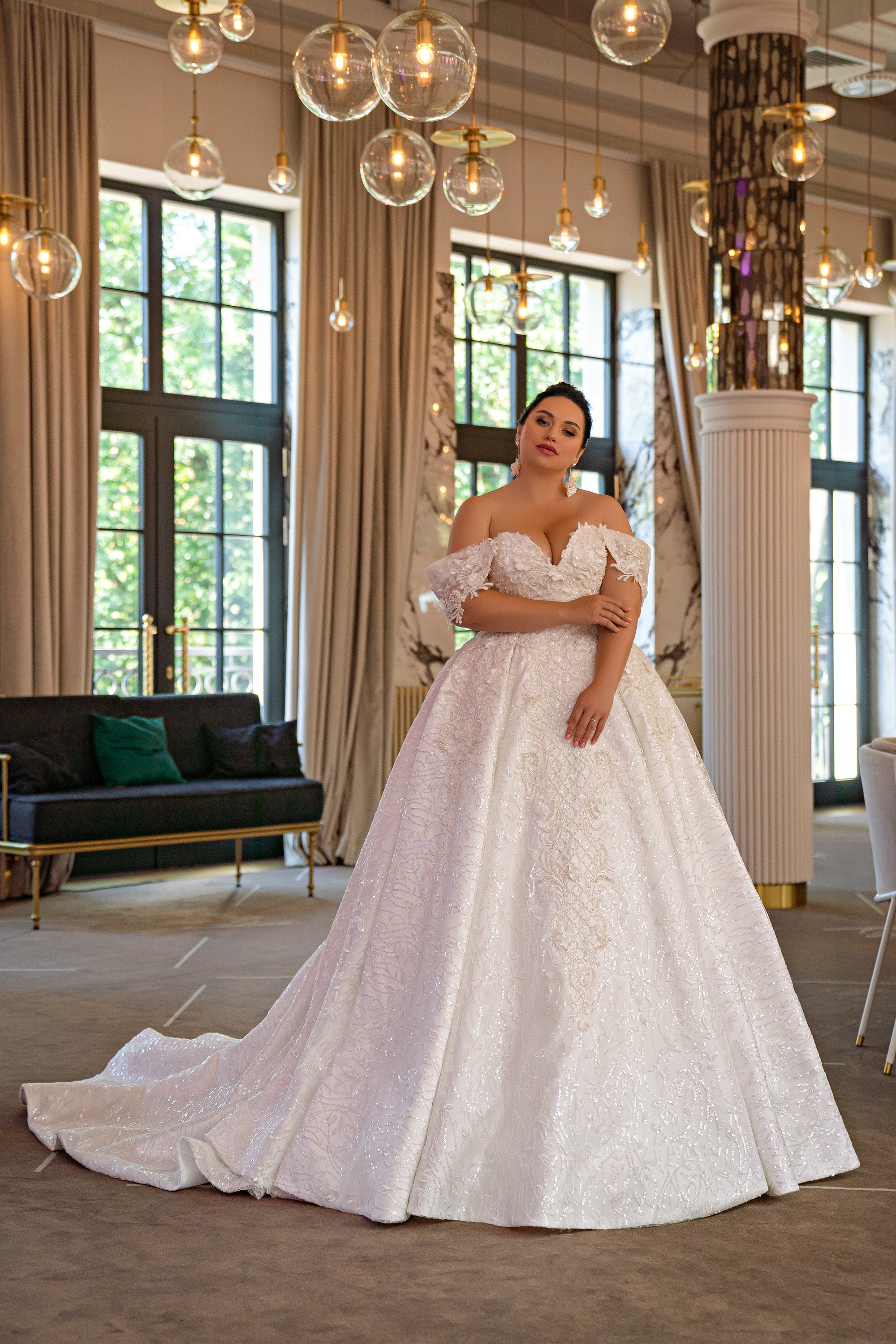 Ivory ball gown wedding dress with an off-shoulder floral bodice, sparkling skirt, and sweeping train