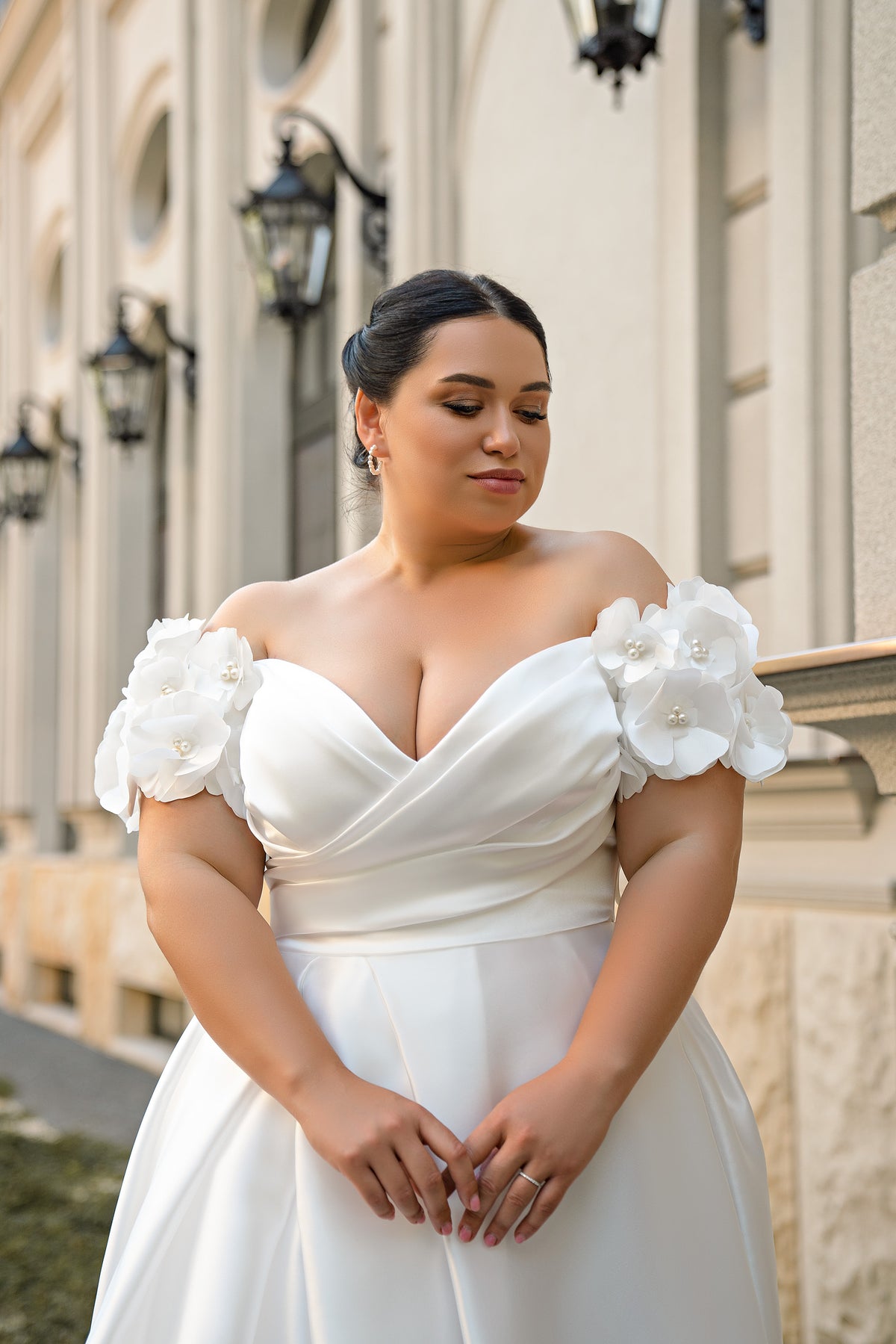 Close-up of a white wedding dress bodice with draped sweetheart neckline and three-dimensional floral sleeves