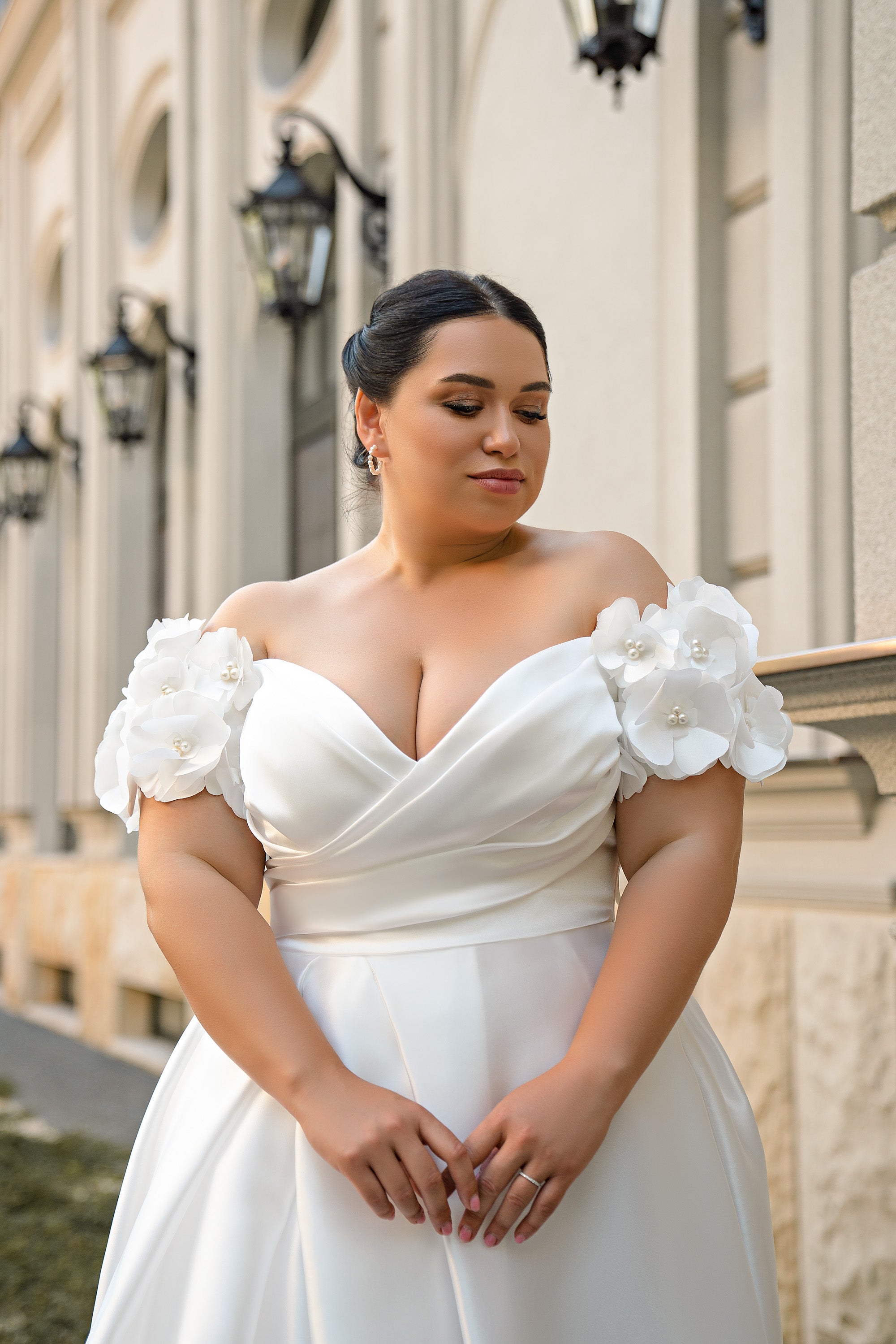 Close-up of a white wedding dress bodice with draped sweetheart neckline and three-dimensional floral sleeves