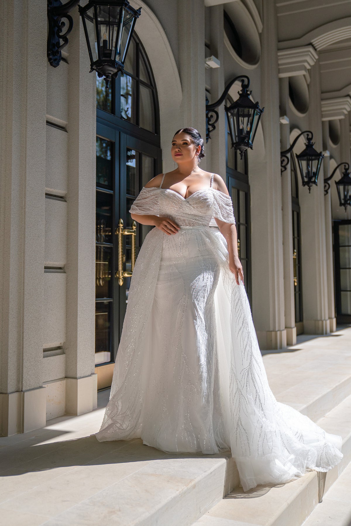 Ivory glitter wedding dress with an off-shoulder neckline, fitted bodice, full skirt, and sweeping train