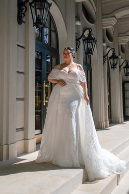 Ivory glitter wedding dress with an off-shoulder neckline, fitted bodice, full skirt, and sweeping train