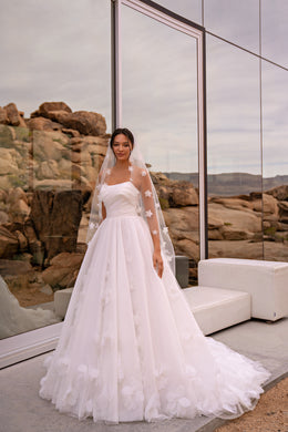 Ivory A-line wedding dress with a ruched bodice, floral tulle skirt, and sweeping chapel train