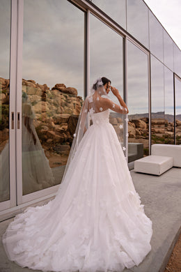 Ivory wedding dress with a full floral-appliqué tulle skirt and extended chapel train seen from behind