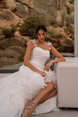 Ivory wedding dress with a ruched bodice, floral shoulder appliqués, and a high side slit