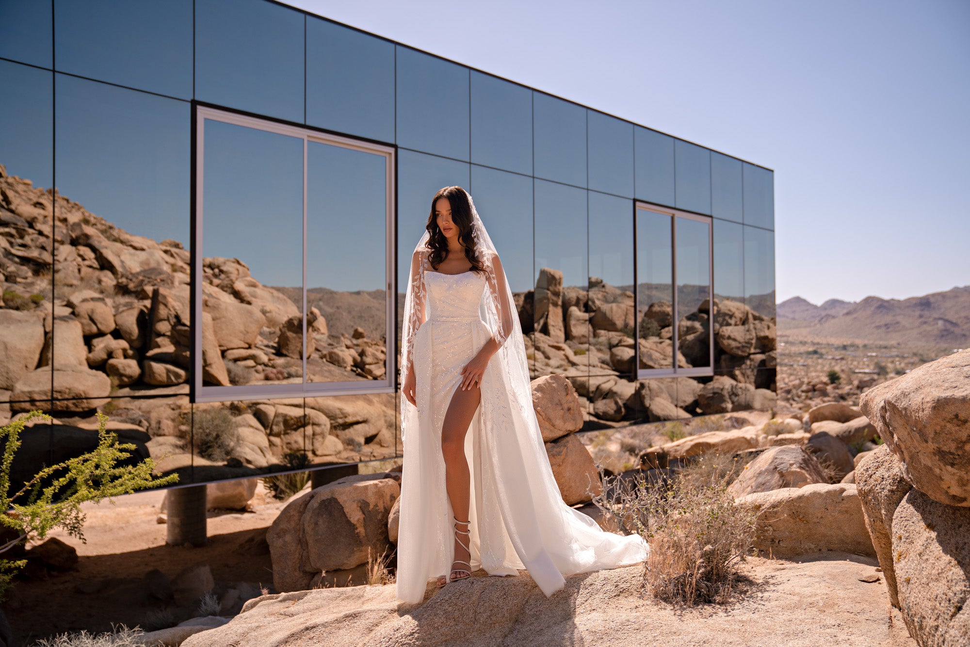White wedding dress with a square neckline, delicate straps, sparkly embellishments, and high slit