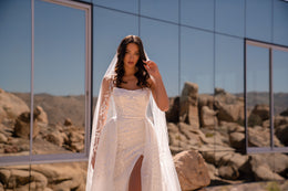 Close-up of a white wedding dress with a square neckline, glittering embroidery, and thigh-high slit