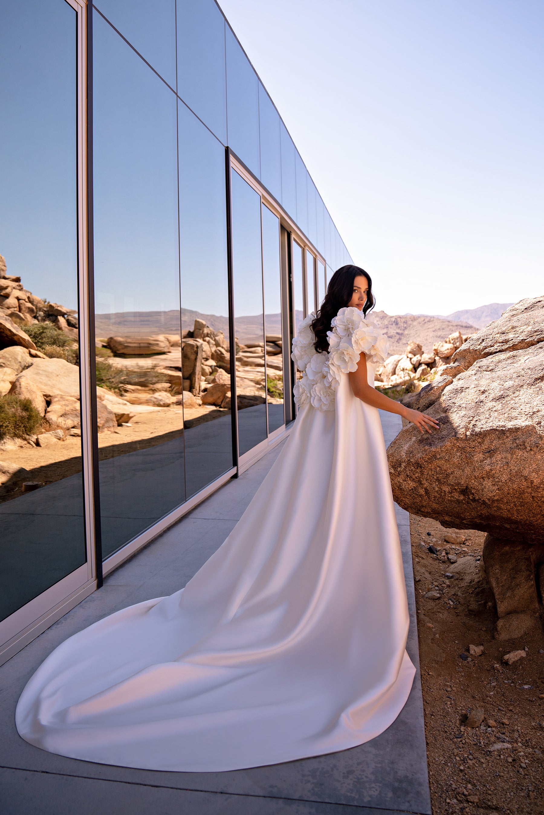 Ivory wedding dress with 3D floral sleeves and a long detachable cape flowing into a wide train