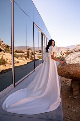 Ivory wedding dress with 3D floral sleeves and a long detachable cape flowing into a wide train