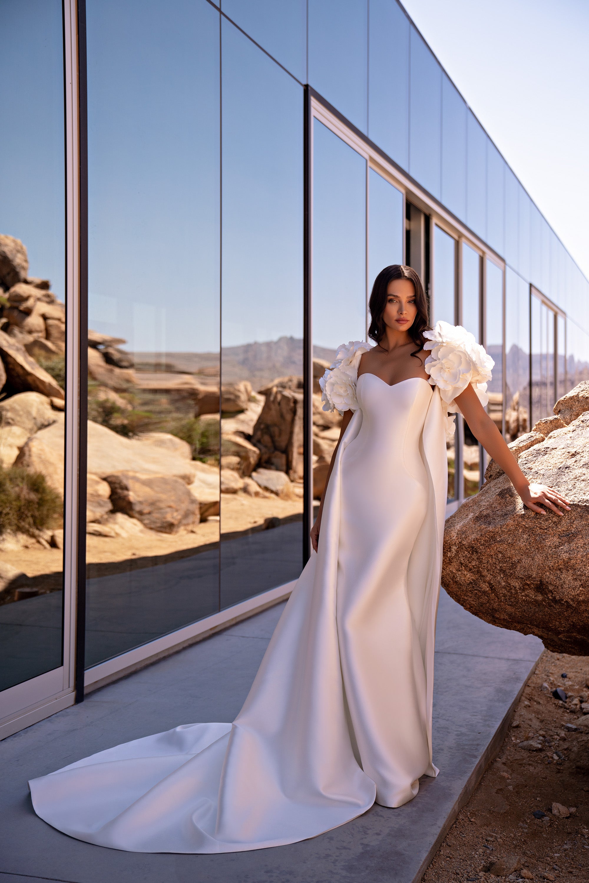 Fitted ivory mermaid wedding dress with a sweetheart neckline, sculptural floral sleeves, and a sweeping train