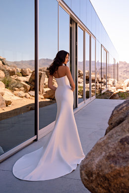 Open-back ivory mermaid wedding dress with a fitted silhouette and a broad, sweeping train