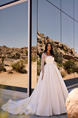 Ivory ball gown wedding dress with a square neckline, sheer sparkling long sleeves, and a sweeping train