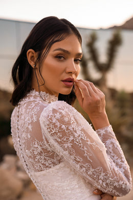 Close-up of floral lace sleeves and sheer embroidered detailing on an ivory wedding dress