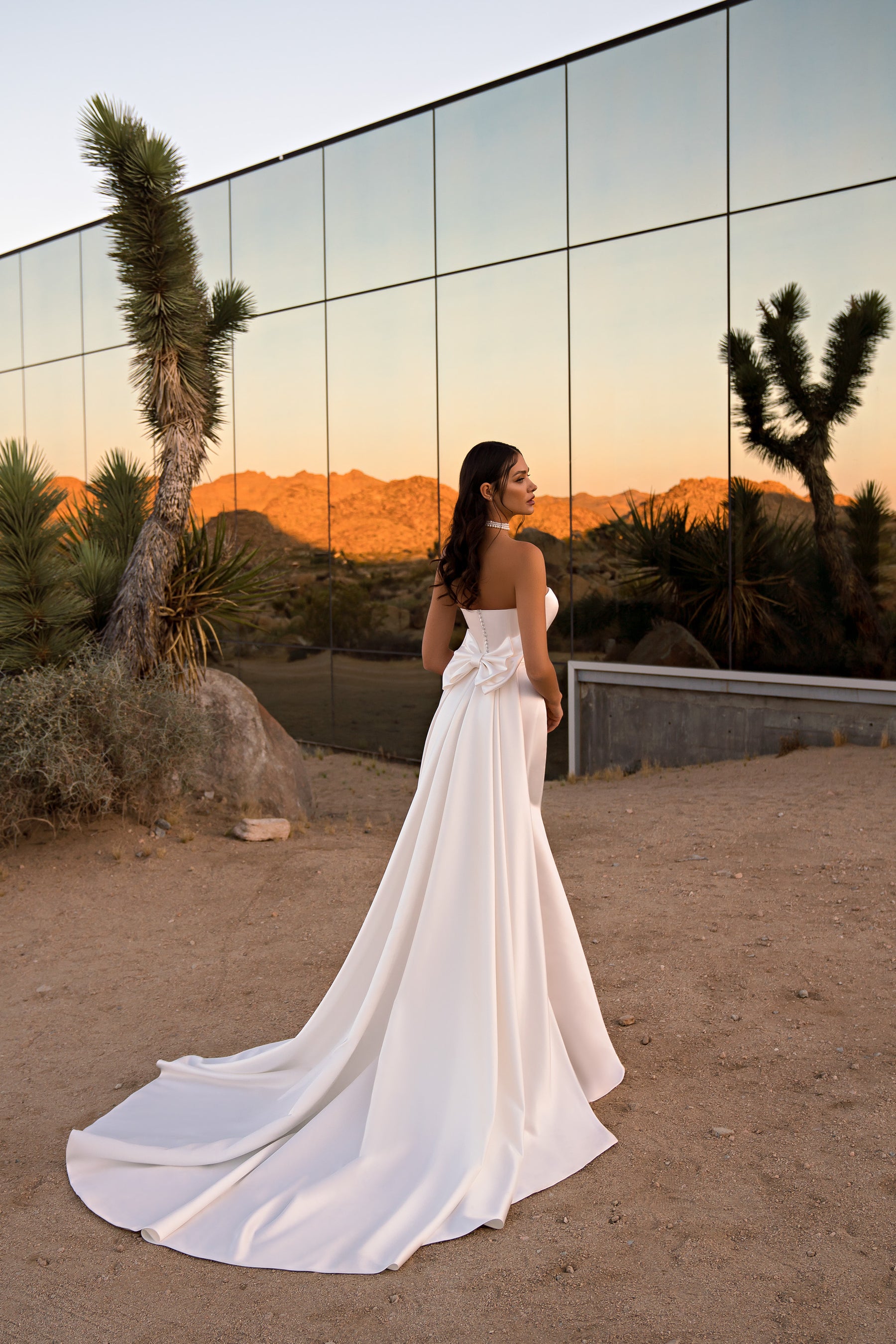 Open-back ivory wedding dress with a fitted waist and dramatically extended train