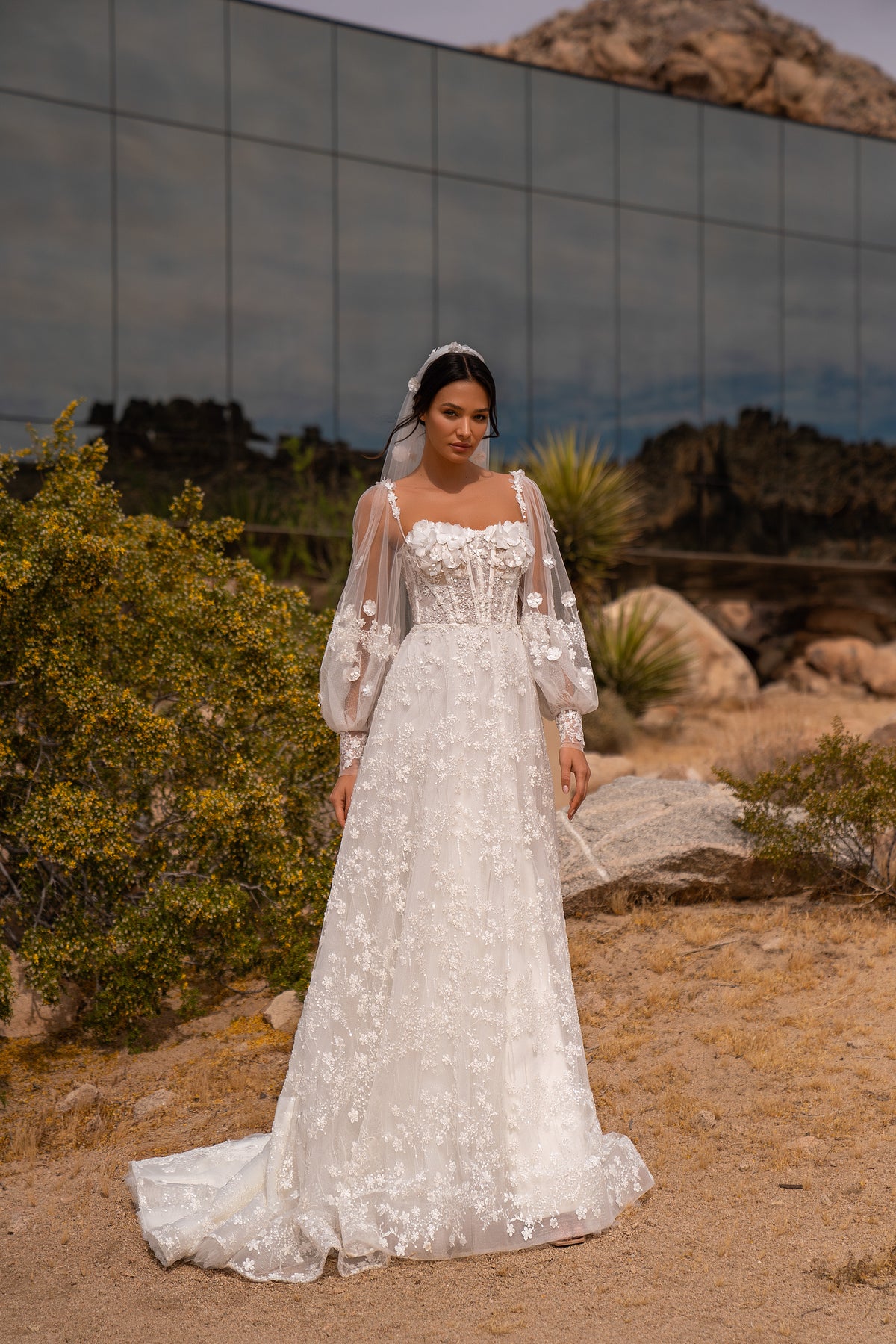 Ivory A-line wedding dress with floral appliqués, sheer bishop sleeves, and a sweeping lace train