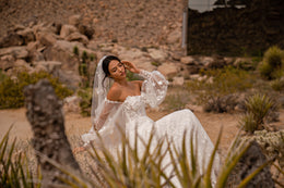 Ivory wedding dress with sheer bishop sleeves, a straight neckline, and a flowing floral-appliqué skirt