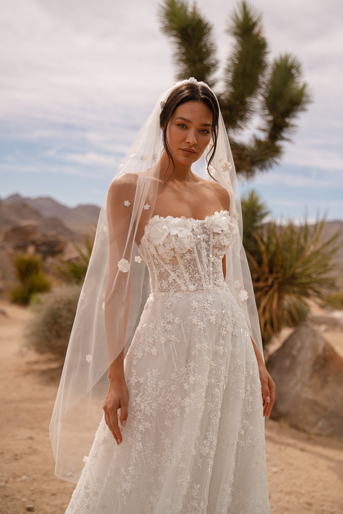 Close-up of an ivory wedding dress with a square neckline, sheer floral sleeves, and an appliqué bodice