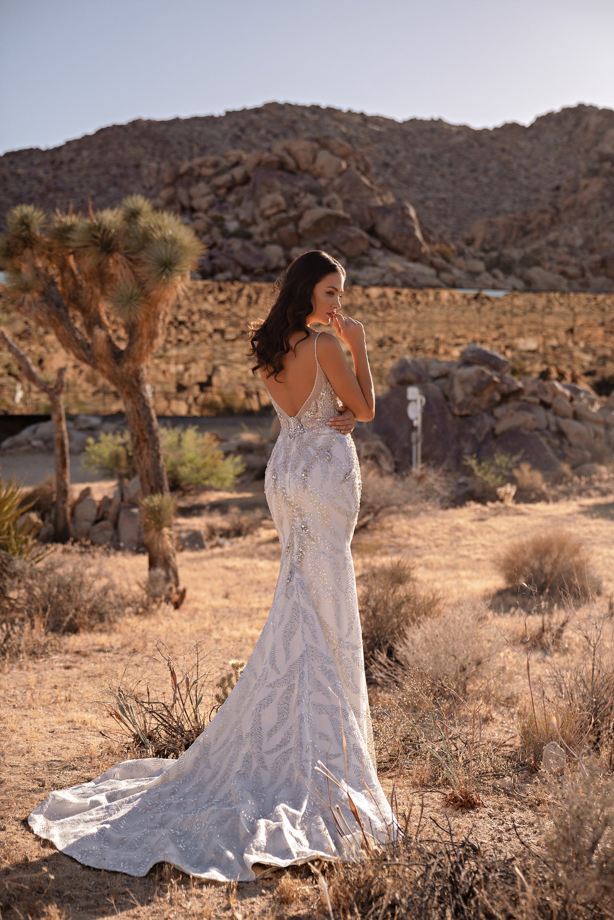 Open-back ivory wedding dress with sparkling beadwork, thin straps, a mermaid skirt, and long train