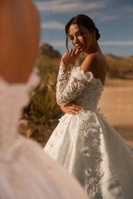 Side view of an ivory wedding dress with floral lace sleeves, appliqués, and a voluminous ball gown skirt