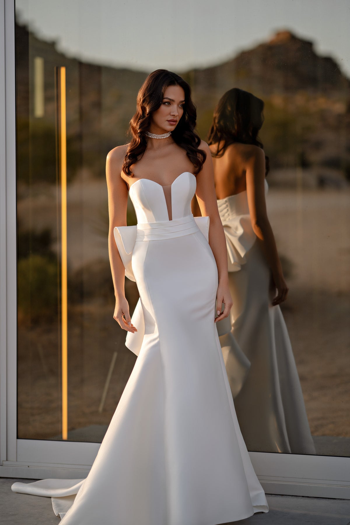 White strapless wedding dress with a plunging bodice, fitted mermaid silhouette, and sweeping train