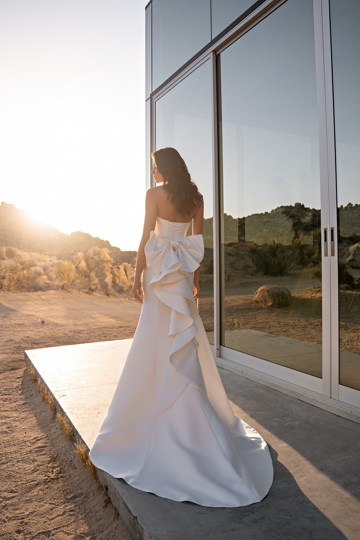 White wedding dress with a large back bow, cascading ruffle detail, and flowing mermaid train