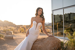 White mermaid wedding dress featuring a deep center plunge and softly draped ruching at the waist