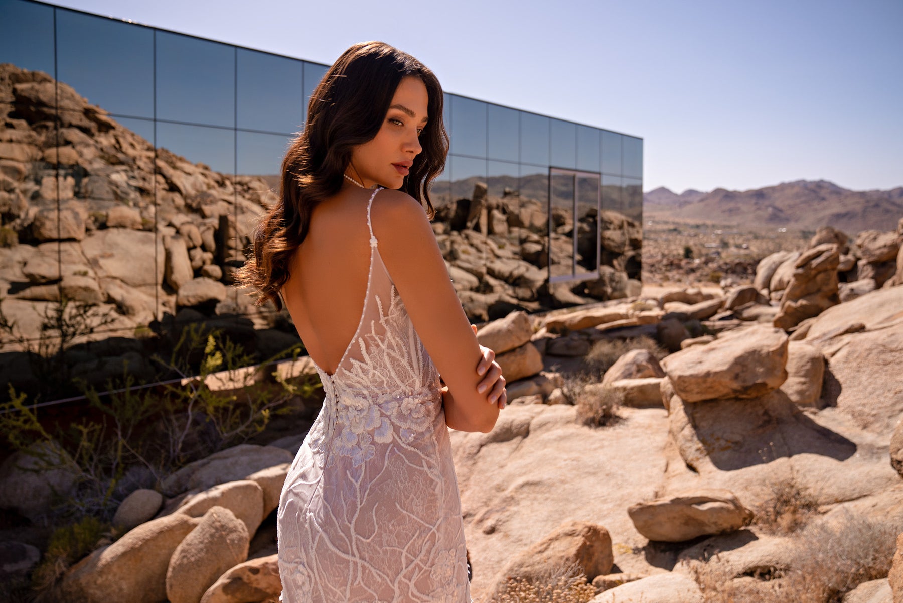 Open-back ivory mermaid wedding dress with thin straps and floral lace detailing