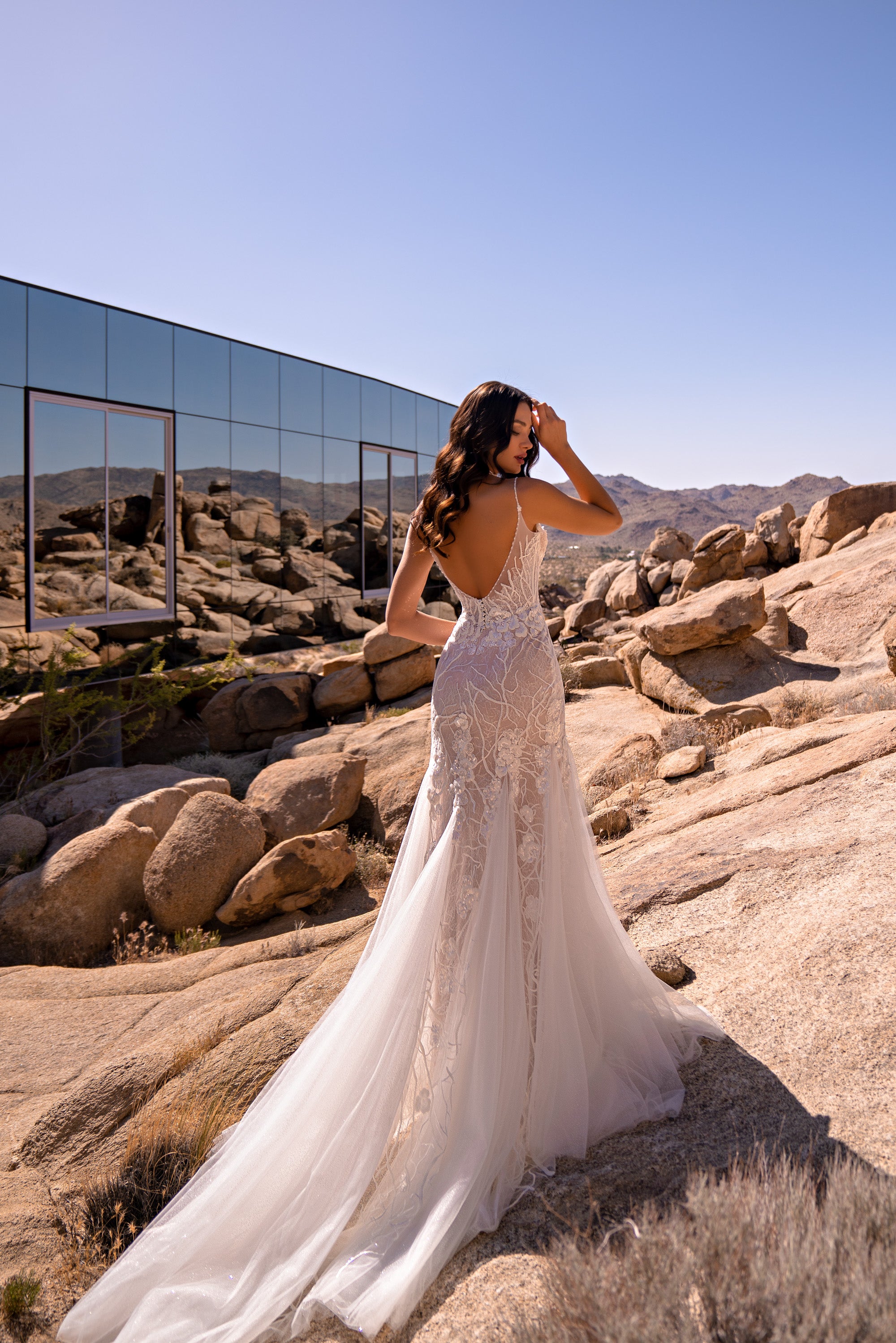 Ivory lace mermaid wedding dress with a low open back, thin straps, and a long flowing train
