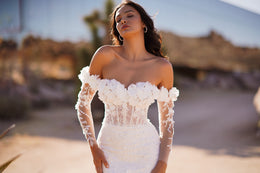 Close-up of an off-the-shoulder wedding dress with sheer floral lace sleeves and a fitted bodice