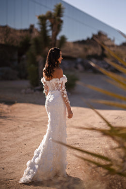 Lace-covered back and fitted mermaid silhouette on an ivory off-the-shoulder wedding dress