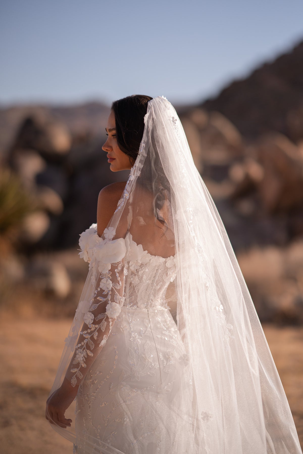 Side profile of an ivory wedding dress with floral lace sleeves and a fitted mermaid skirt