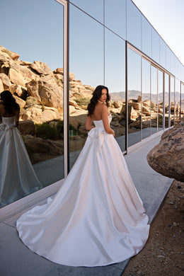 Back view of a white A-line wedding dress featuring a large bow and a sweeping train