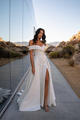 Ivory off-the-shoulder wedding dress with a wrap bodice, sparkling floral embellishments, high slit, and train