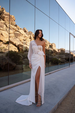 Ivory one-shoulder wedding dress with a lace long sleeve, ruched skirt, high slit, and train