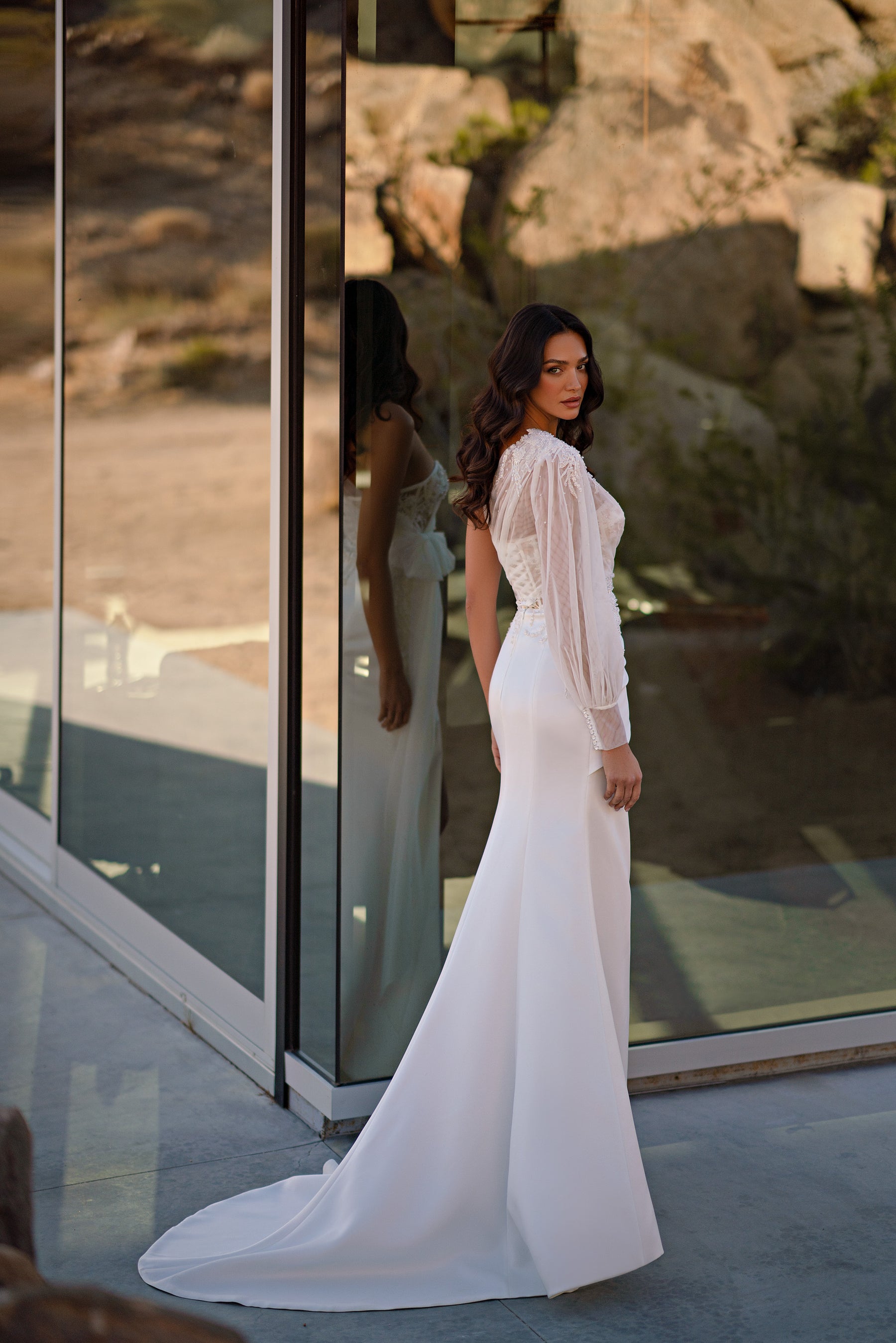 Side view of an ivory wedding dress with a fitted skirt, lace long sleeve, and sweeping train