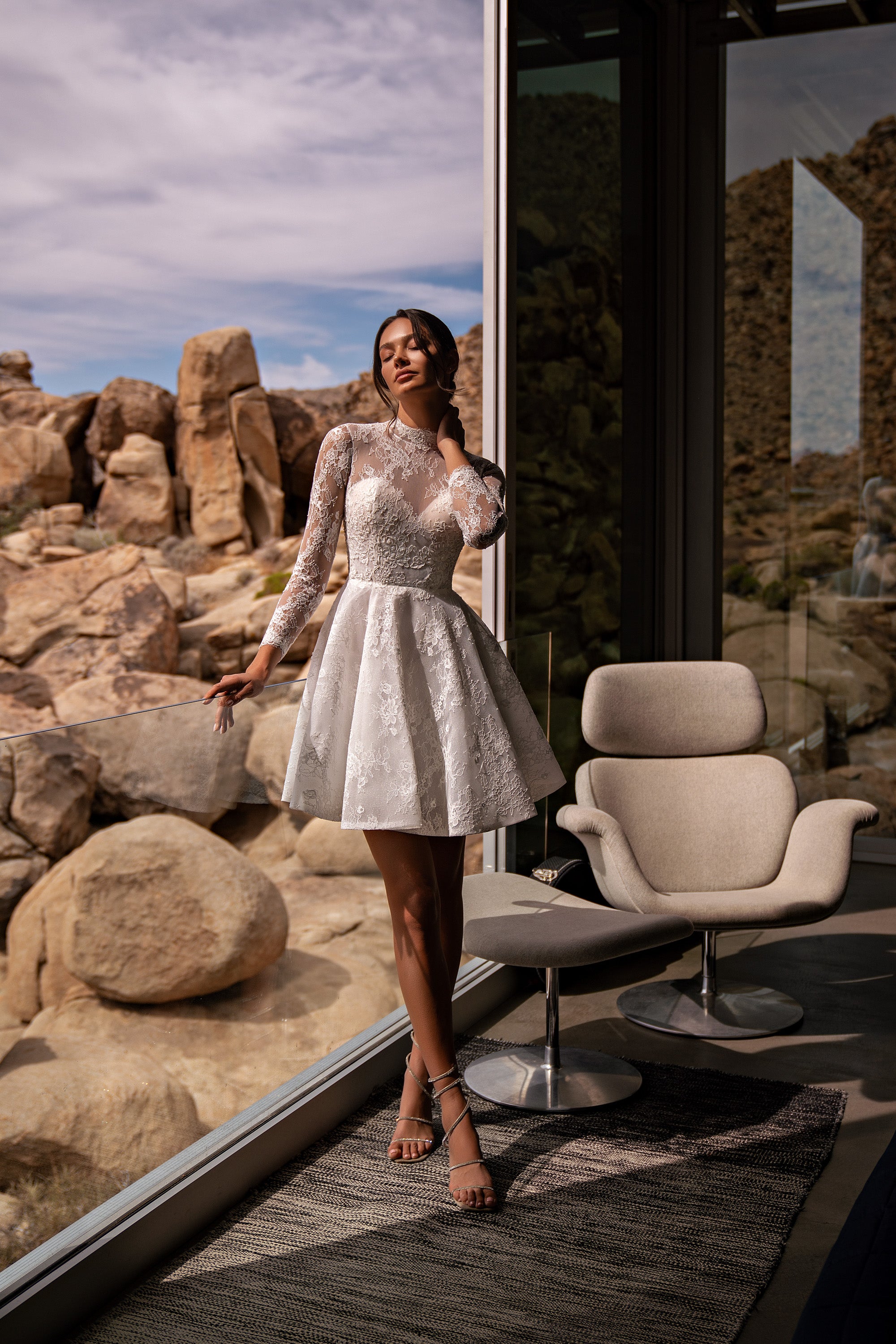 White high-neck wedding dress with long lace sleeves, fitted waist, and flared mini skirt