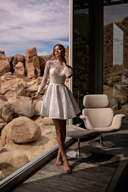 White high-neck wedding dress with long lace sleeves, fitted waist, and flared mini skirt
