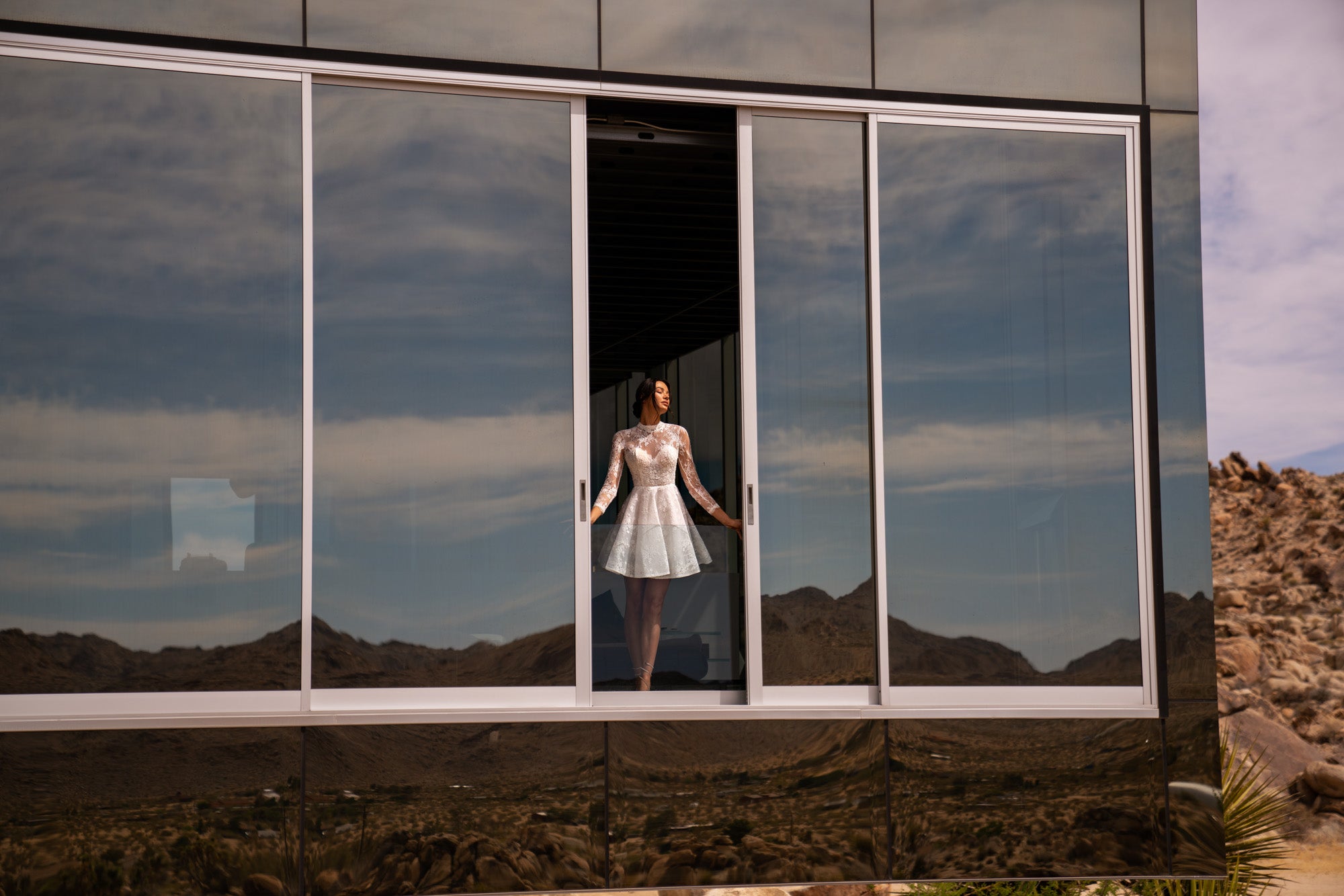 White lace wedding dress with long sleeves, high neckline, and flared mini skirt