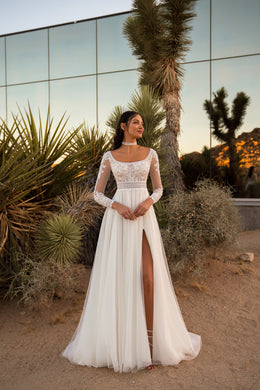 Ivory A-line wedding dress with an illusion lace bodice, long sleeves, scoop neckline, and thigh-high slit