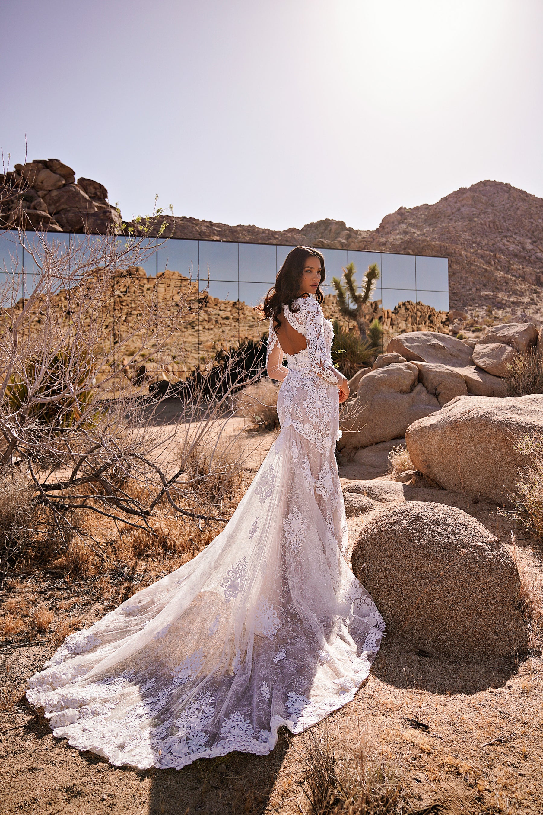 Ivory wedding dress with a low open back, long lace sleeves, mermaid silhouette, and extended lace train