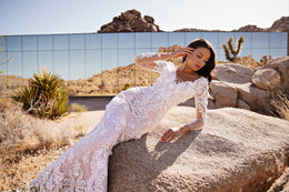 Fitted ivory lace wedding dress with long sleeves, floral lace detailing, and a flared mermaid hem