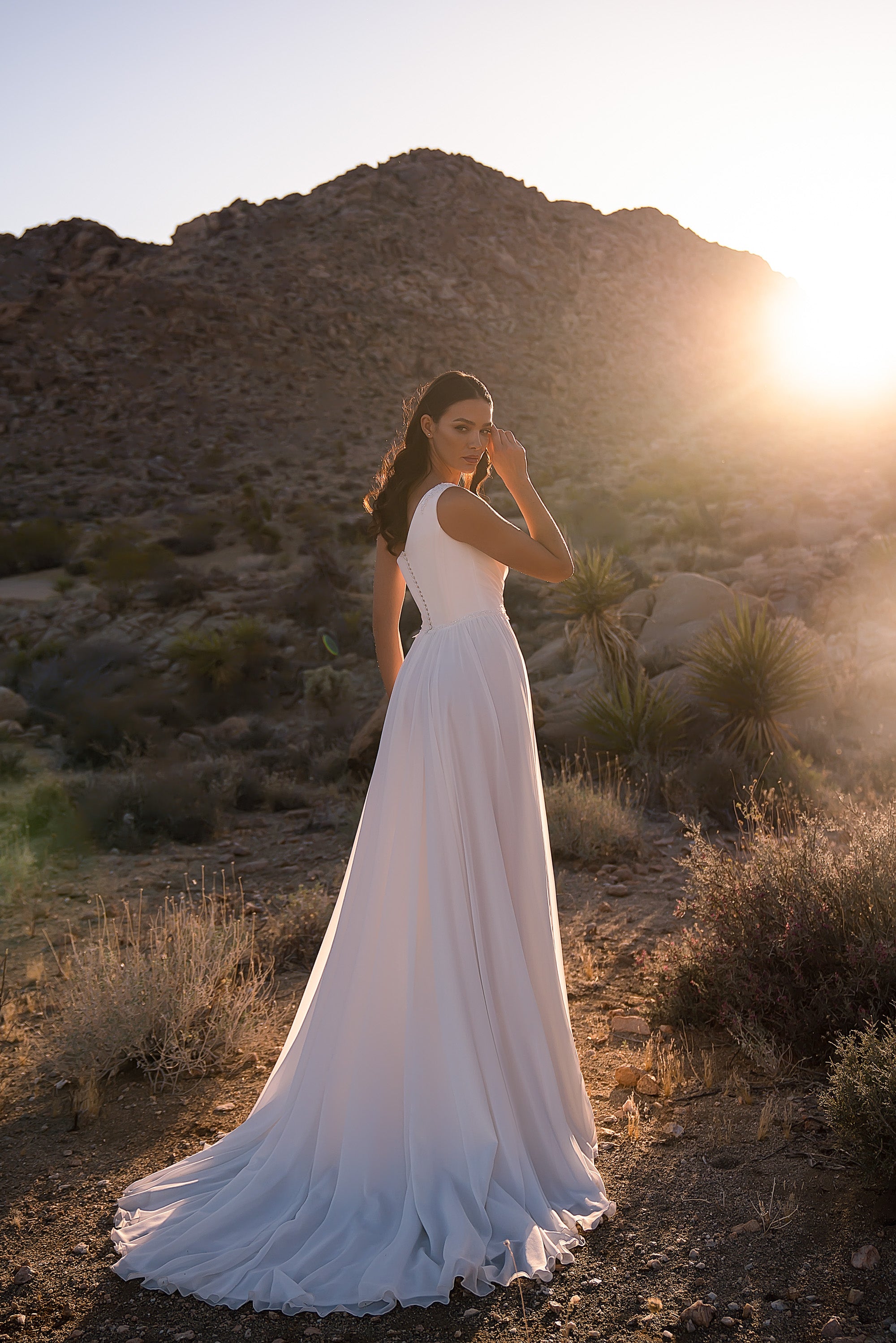 White wedding dress shown from behind with a fitted waist, flowing A-line skirt, and long train