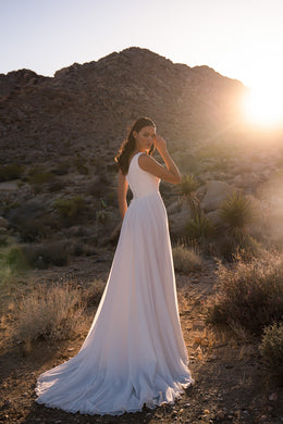 White wedding dress shown from behind with a fitted waist, flowing A-line skirt, and long train