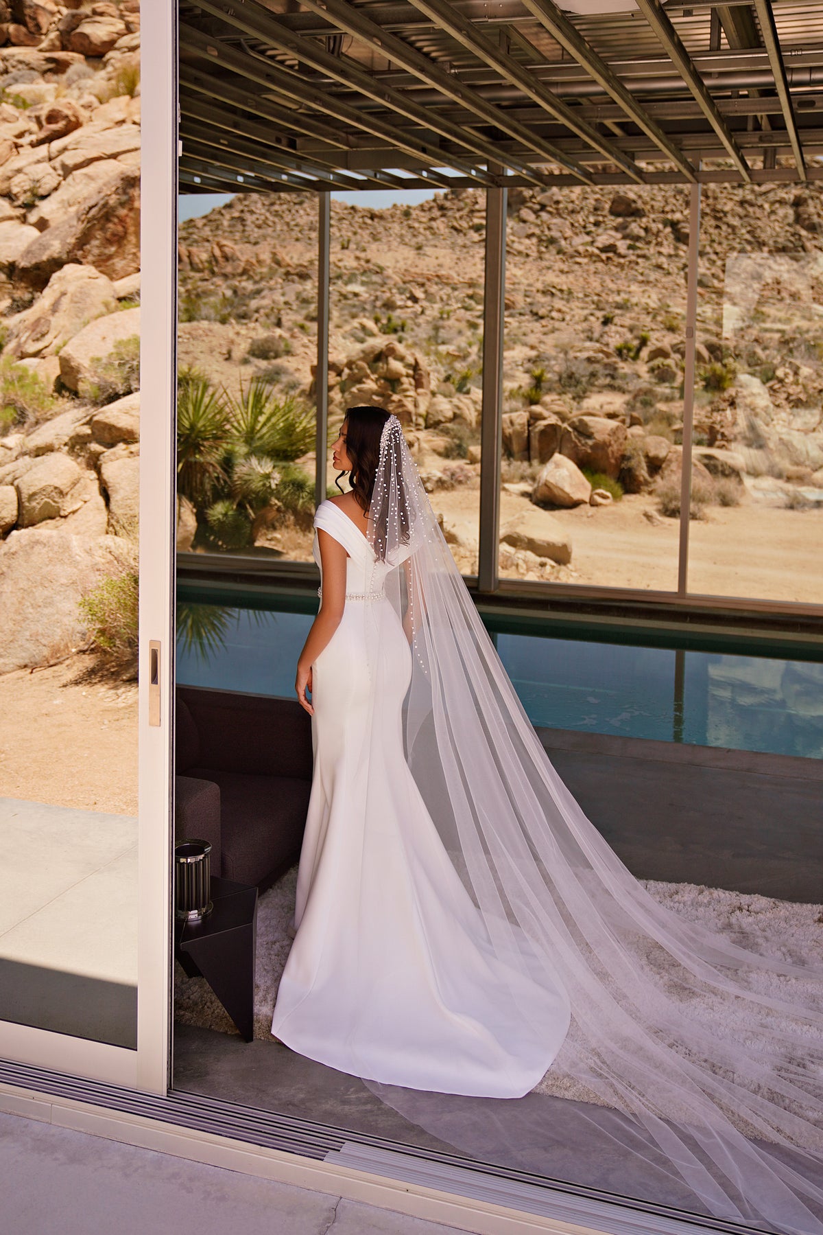 Back view of a white mermaid wedding dress with a long train and floor-length dotted veil