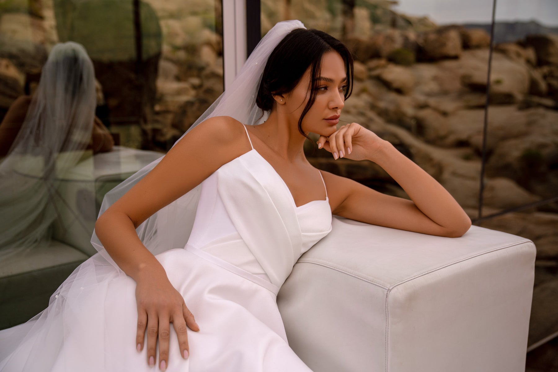 Close-up of a white wedding dress bodice with slim straps, a square neckline, and softly draped fabric