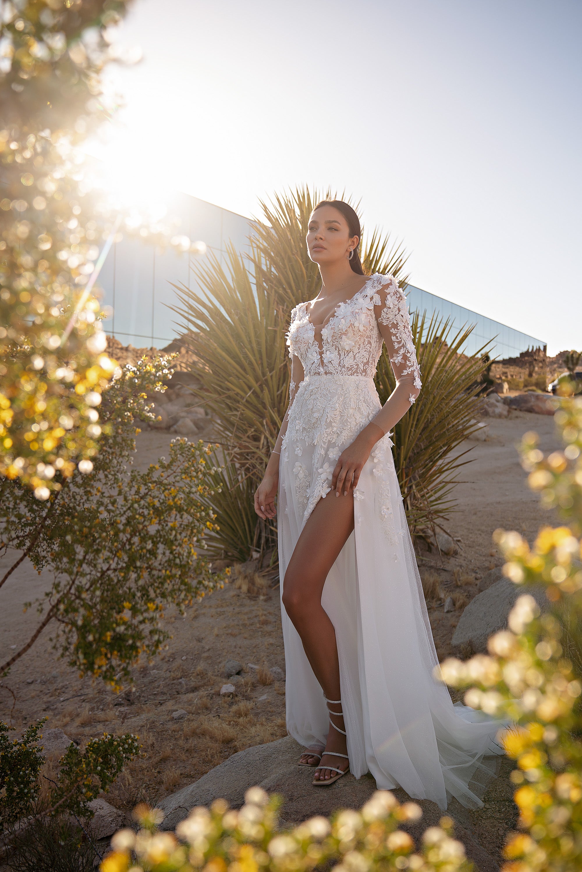 Ivory wedding dress with floral lace sleeves, fitted bodice, high thigh slit, and flowing train