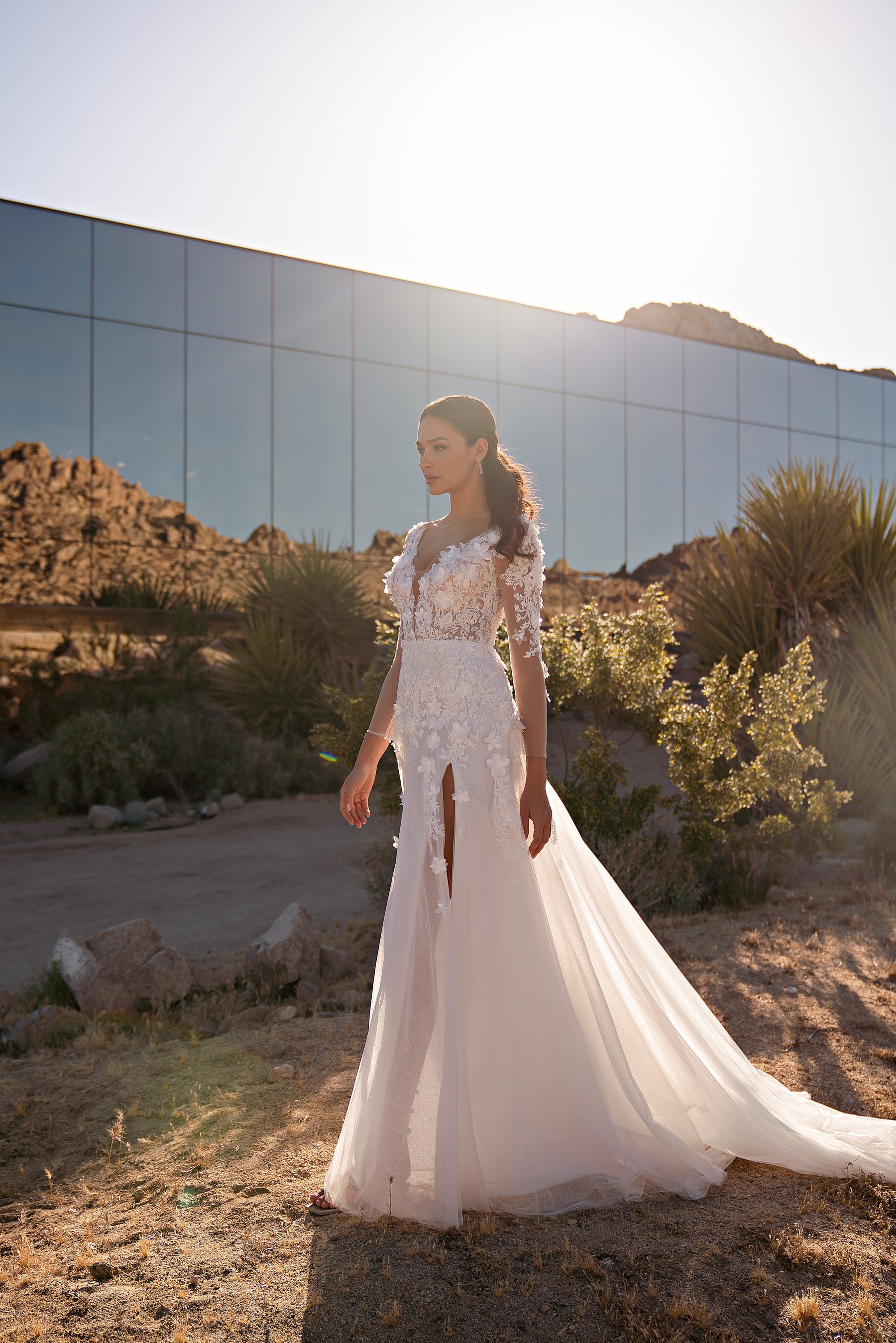 Side view of an ivory wedding dress with sheer floral lace sleeves, thigh-high slit, and sweeping train