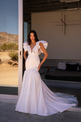 White mermaid wedding dress with a plunging V-neck, ruffled sleeves, beaded bodice, and long train