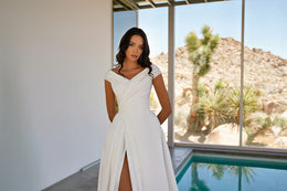 Ivory wedding dress with a crossover draped neckline, short sleeves, fitted waist, and front slit