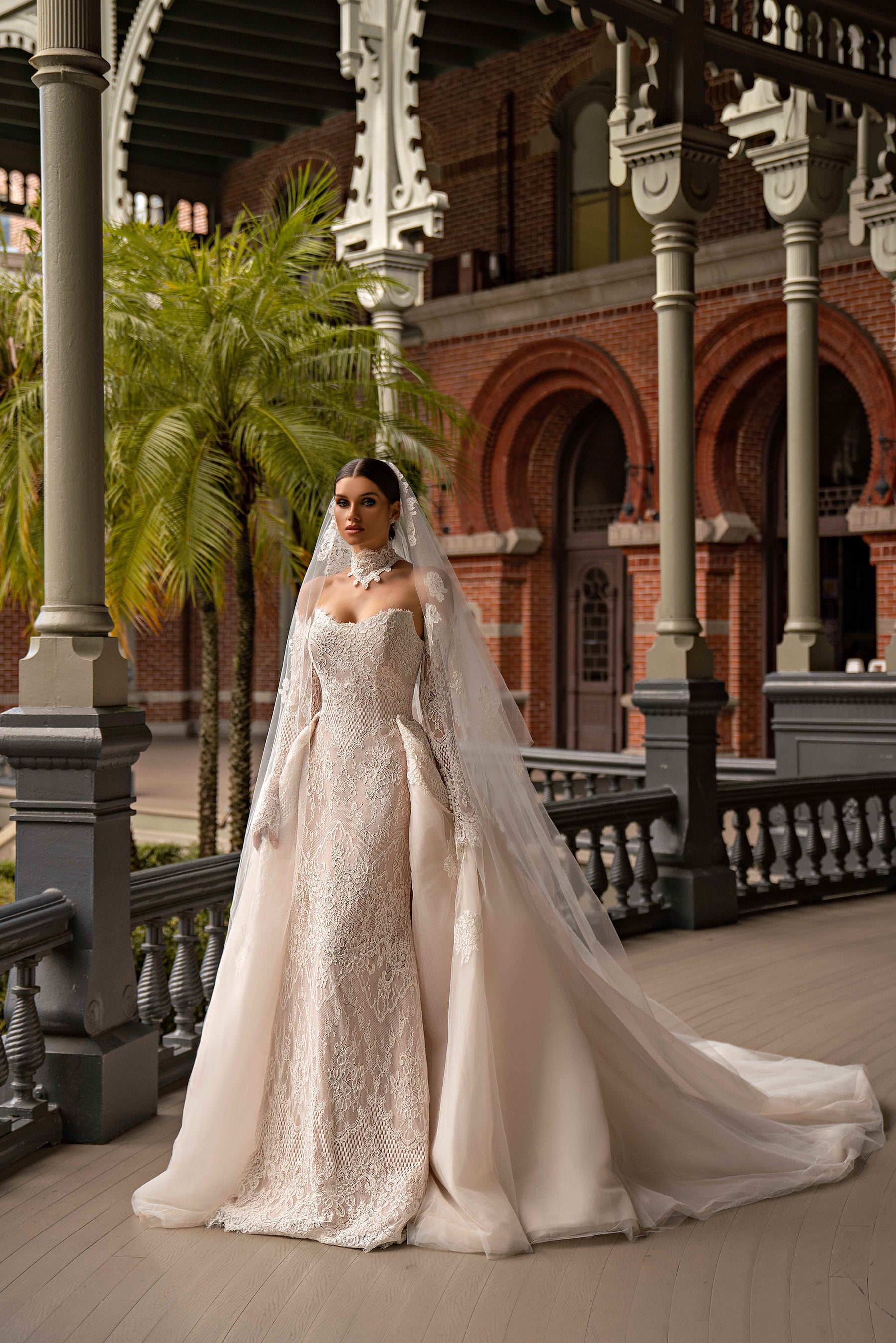 Ivory lace sheath wedding dress with a fitted bodice, long sleeves, and a sheer overskirt