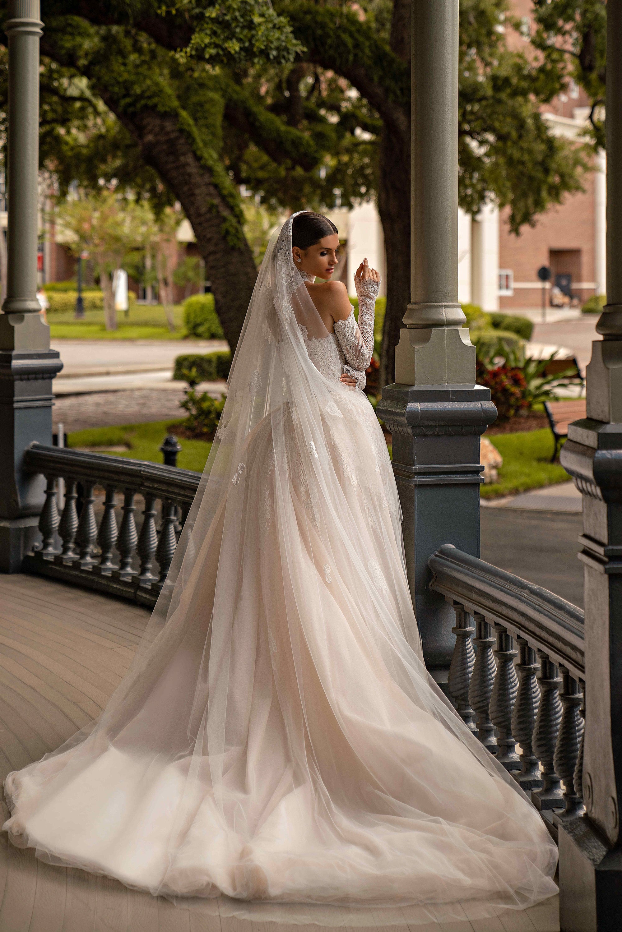 Ivory wedding dress with a sheer full-length overlay draping over the fitted lace gown and train